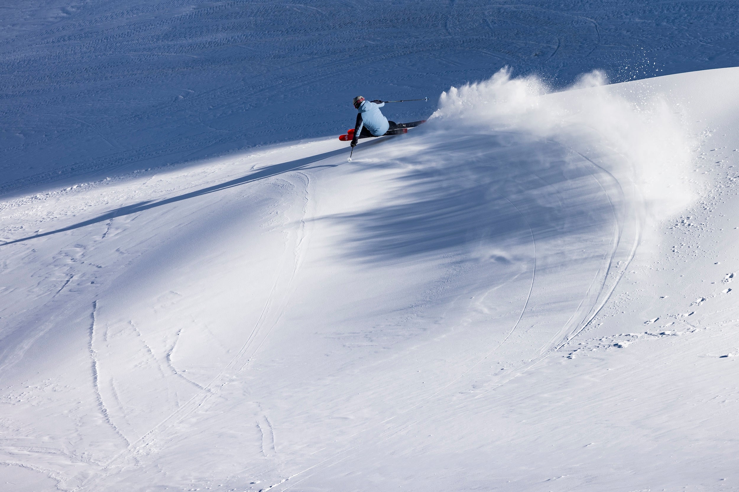 Person skiing down a snowy slope with a large splash of snow behind them